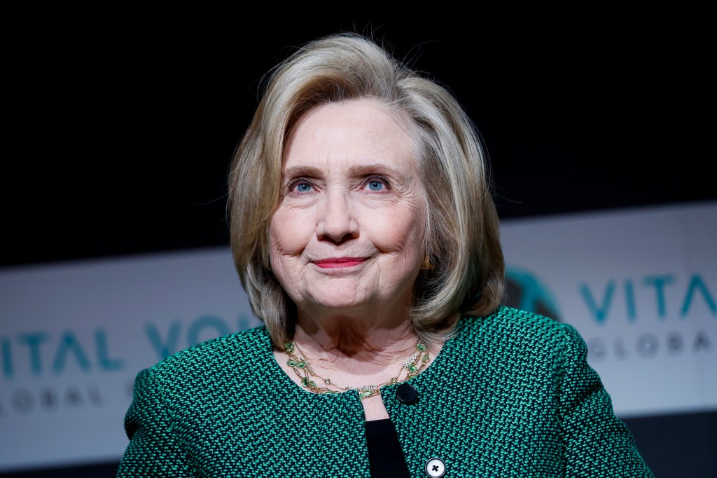 Hillary Clinton giving a speech at the Global Vital Voices Festival in Washington, DC, wearing a green jacket